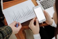 Seorang pengusaha sedang menganalisis data digital di layar tabletnya, menunjukkan fokus pada strategi berbasis data untuk mengoptimalkan kinerja bisnis. Latar belakang kota modern merepresentasikan lingkungan bisnis yang dinamis dan terhubung.