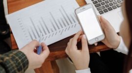Seorang pengusaha sedang menganalisis data digital di layar tabletnya, menunjukkan fokus pada strategi berbasis data untuk mengoptimalkan kinerja bisnis. Latar belakang kota modern merepresentasikan lingkungan bisnis yang dinamis dan terhubung.