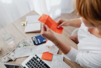 Seorang pemilik usaha kecil sedang serius menghitung laporan keuangan di hadapan laptopnya, menunjukkan dedikasi dalam mengelola aspek finansial bisnisnya. Gambaran ini merefleksikan pentingnya ketelitian dalam pencatatan dan analisis keuangan bagi keberlanjutan UMKM.