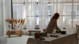 Seorang perempuan sedang sibuk merangkai bunga di meja kerjanya yang tertata rapi di sudut rumah, menggambarkan bagaimana hobi dapat diubah menjadi usaha rumahan yang produktif. Ruangan tersebut dipenuhi dengan berbagai jenis bunga segar dan alat-alat merangkai, menunjukkan suasana kreatif yang mendukung pengembangan bisnis.