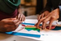 Sebuah tim sedang berdiskusi intens di depan layar monitor yang menampilkan berbagai grafik dan data analitik, menggambarkan proses perencanaan strategi bisnis digital yang komprehensif. Momen ini merefleksikan pentingnya kolaborasi dan data dalam mengambil keputusan strategis di era digital.