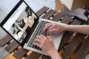 Seorang pemilik UMKM sedang mengoperasikan laptopnya di sebuah kedai kopi yang nyaman, menggambarkan dedikasi dalam mengelola pemasaran online produk lokalnya. Gambar ini merefleksikan bagaimana teknologi menjadi alat vital bagi pelaku usaha kecil untuk mengembangkan jangkauan pasar mereka.
