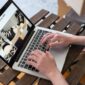 Seorang pemilik UMKM sedang mengoperasikan laptopnya di sebuah kedai kopi yang nyaman, menggambarkan dedikasi dalam mengelola pemasaran online produk lokalnya. Gambar ini merefleksikan bagaimana teknologi menjadi alat vital bagi pelaku usaha kecil untuk mengembangkan jangkauan pasar mereka.