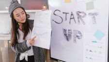 Seorang wirausahawan muda sedang mempresentasikan ide bisnisnya dengan penuh semangat, menunjukkan bahwa kreativitas dan inovasi bisa menjadi modal utama dalam merintis usaha. Ia menggunakan gestur tangan untuk menekankan poin penting dalam presentasinya.